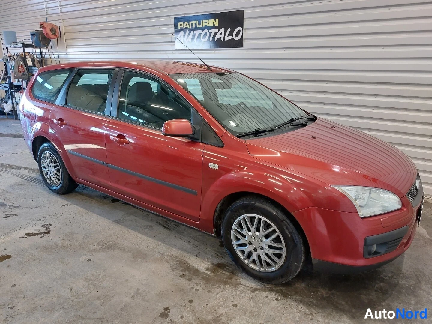 Etuviisto, nokka oikealle: Punainen Ford Focus -farmari etuviistosta oikealta, kylki ja keulan etupansi ja ajovalot näkyvät.