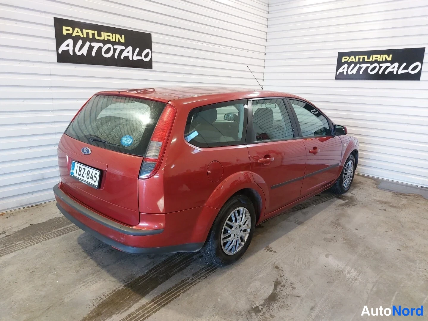 Takaviisto: Punainen Ford Focus -farmari takaviistosta vasemmalta, rekisterikilpi näkyvissä.