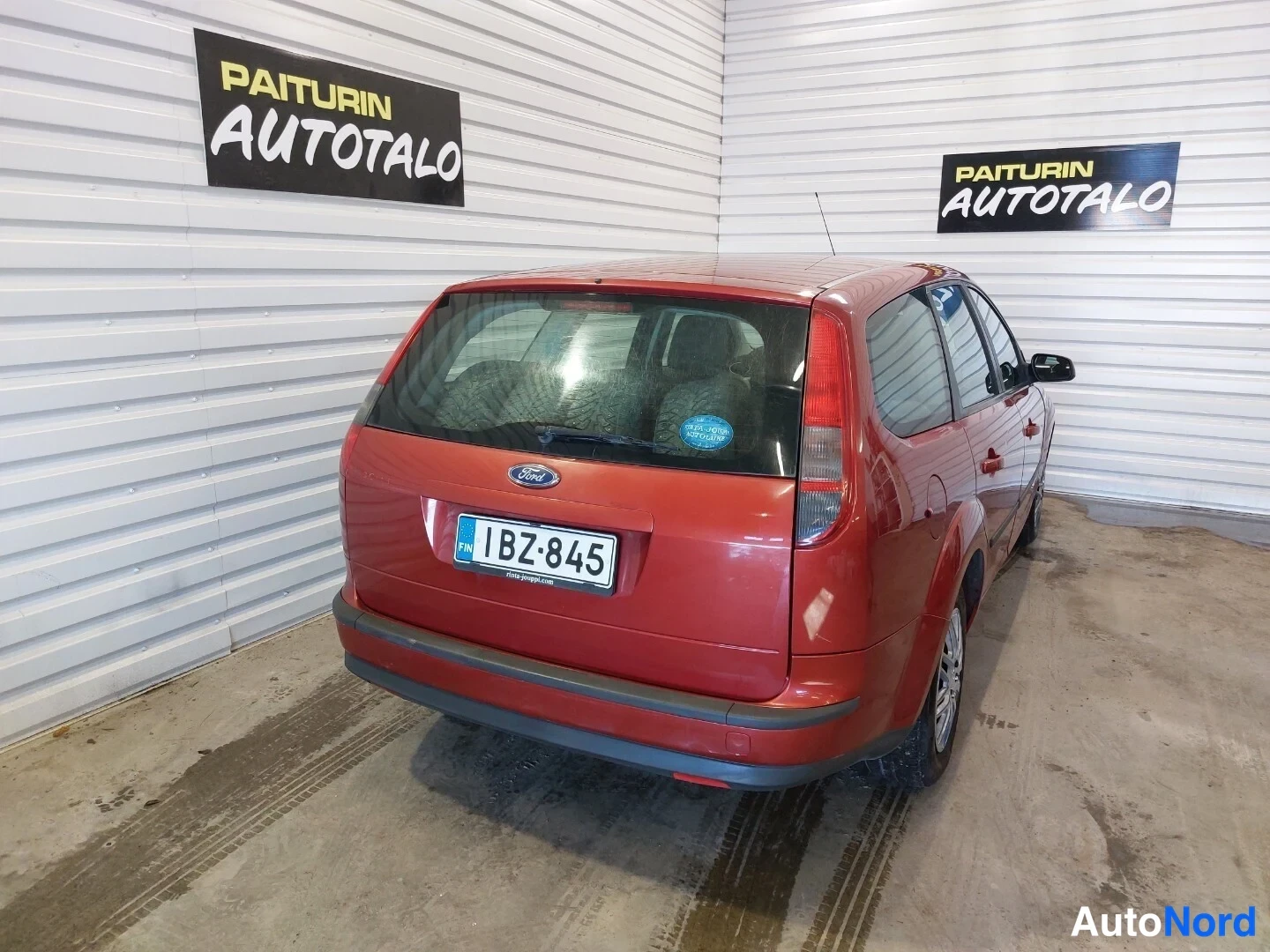 Takaa: Punaisen Ford Focus -farmarin takapuoli suoraan, rekisterikilpi ja Ford-merkki näkyvissä.