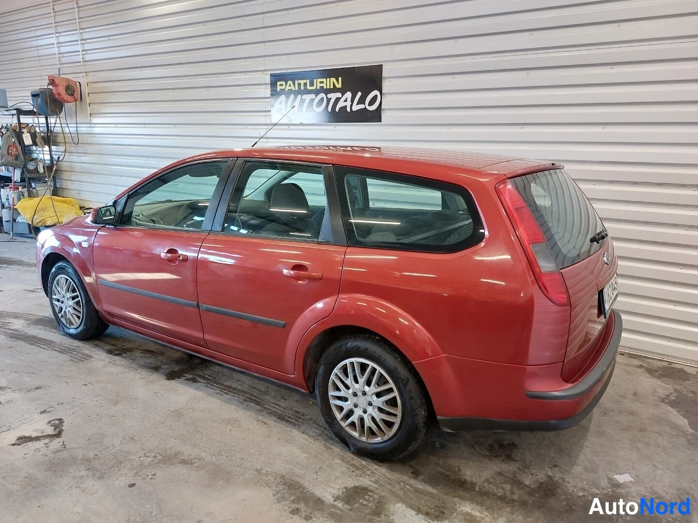 Takaviisto: Punainen farmariauto sivulta ja takaa kuvattuna autotallissa; takavalot, takaluukku ja molemmat takarenkaat näkyvissä.
