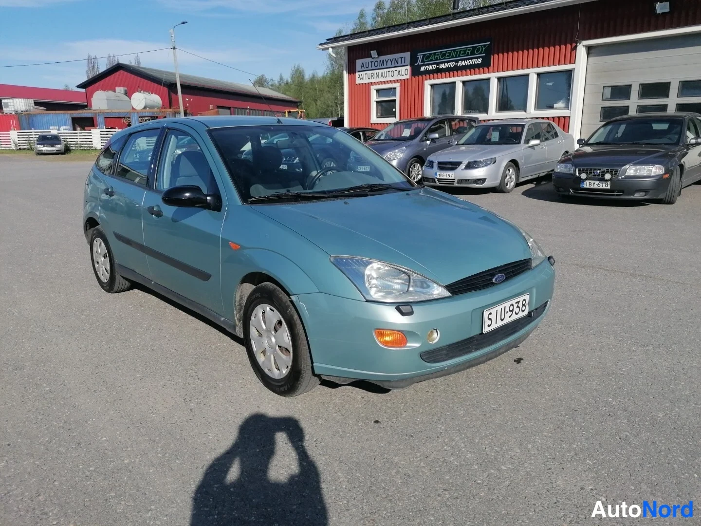 Etuviisto, nokka oikealle: Sinivihreä Ford Focus viistosti edestä oikealta autotallin pihalla.