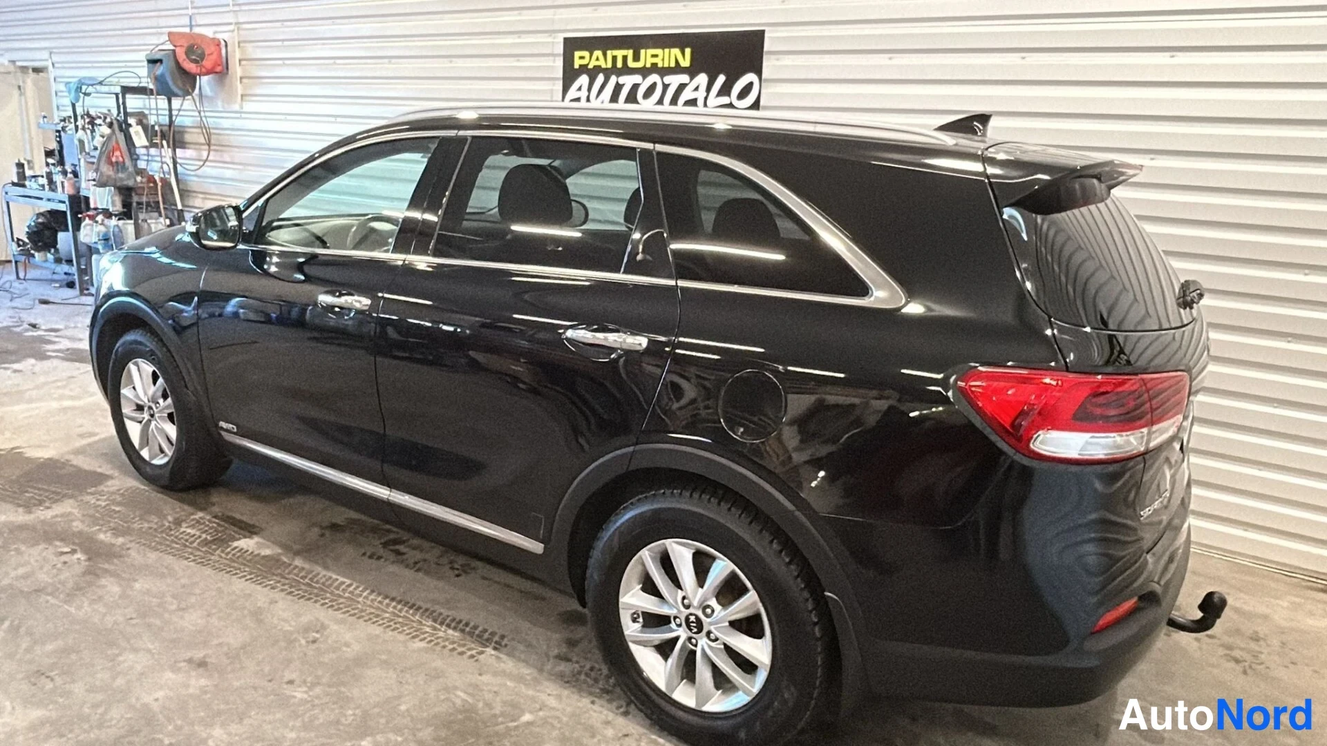 Takaviisto: Kia Sorento -maasturin takaosakulmanäkymä sisätiloissa; musta kori, punaiset takavalot ja takavaijeri näkyvät.