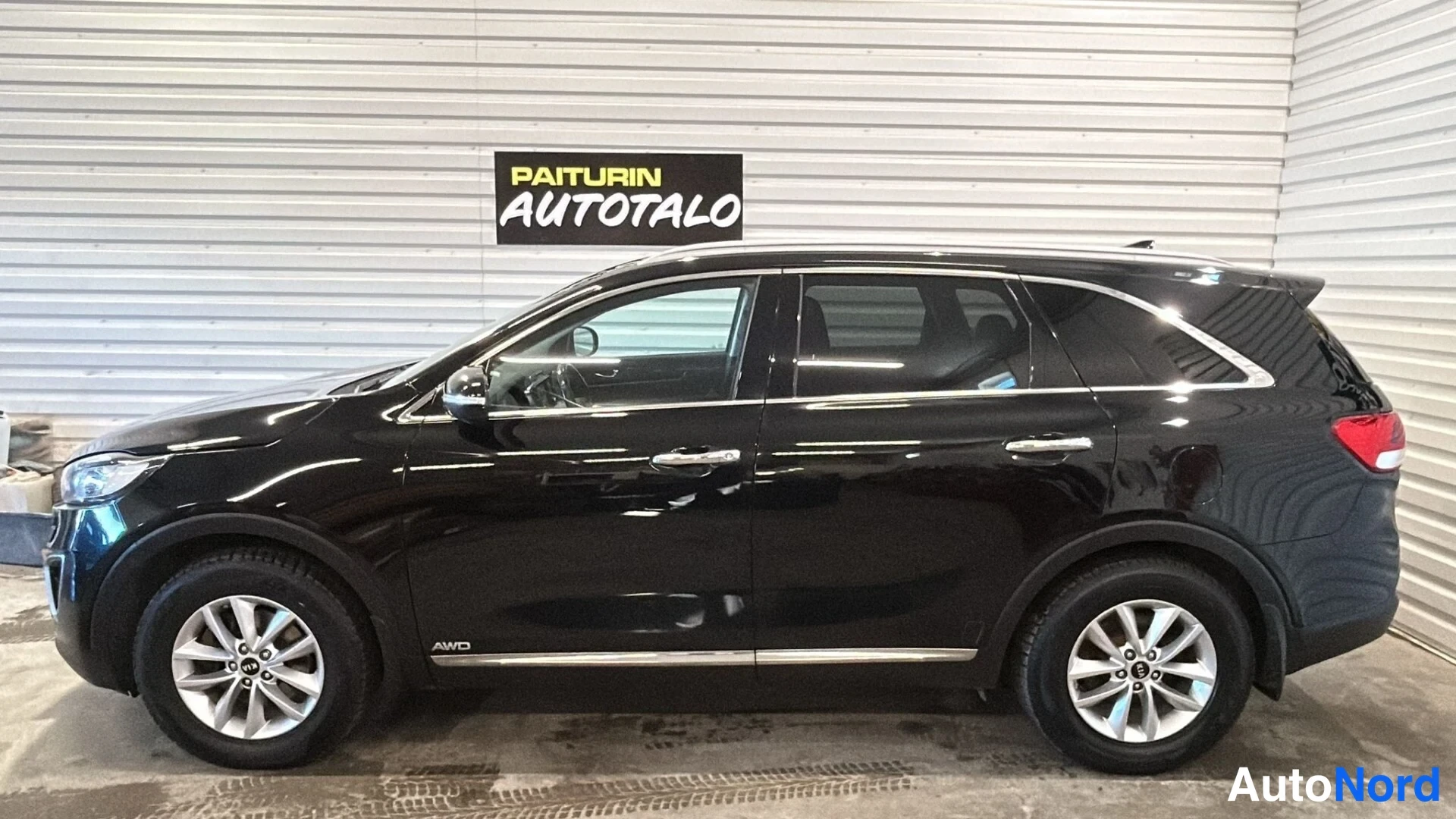 Sivulta: Kia Sorento -maasturin sivuprofiili sisätiloissa; musta kori ja hopeavanteet näkyvät.