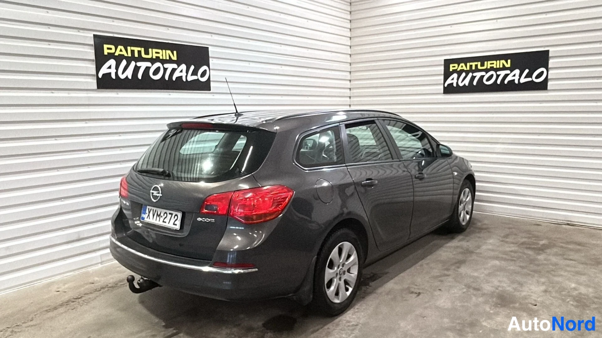 Takaviisto: Auton perä ja vasen sivu; tummanharmaa farmariauto, rekisterikilpi, takana vetokoukku.