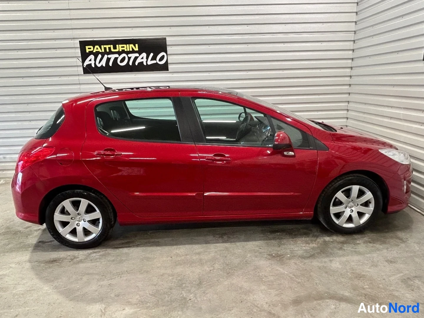 Sivulta: Punaisen Peugeot 308:n sivuprofiili vasemmalta autotallissa.