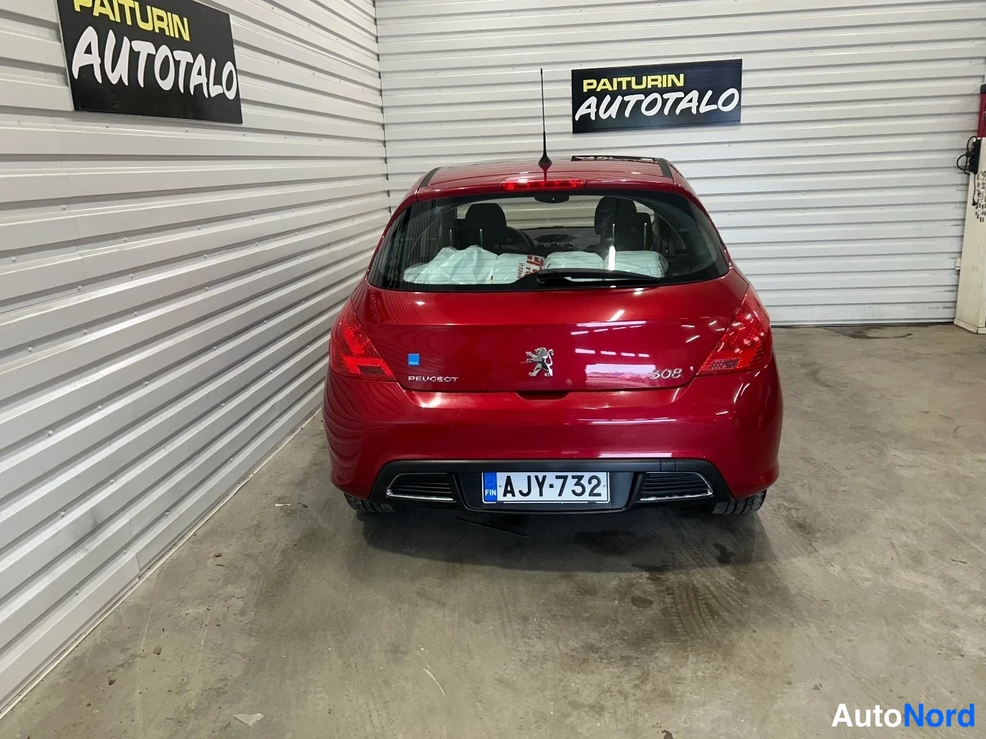 Takaa: Punaisen Peugeot 308:n takaapäin kuva; takaluukussa PEUGEOT- ja 308-tekstit sekä rekisterikilpi.