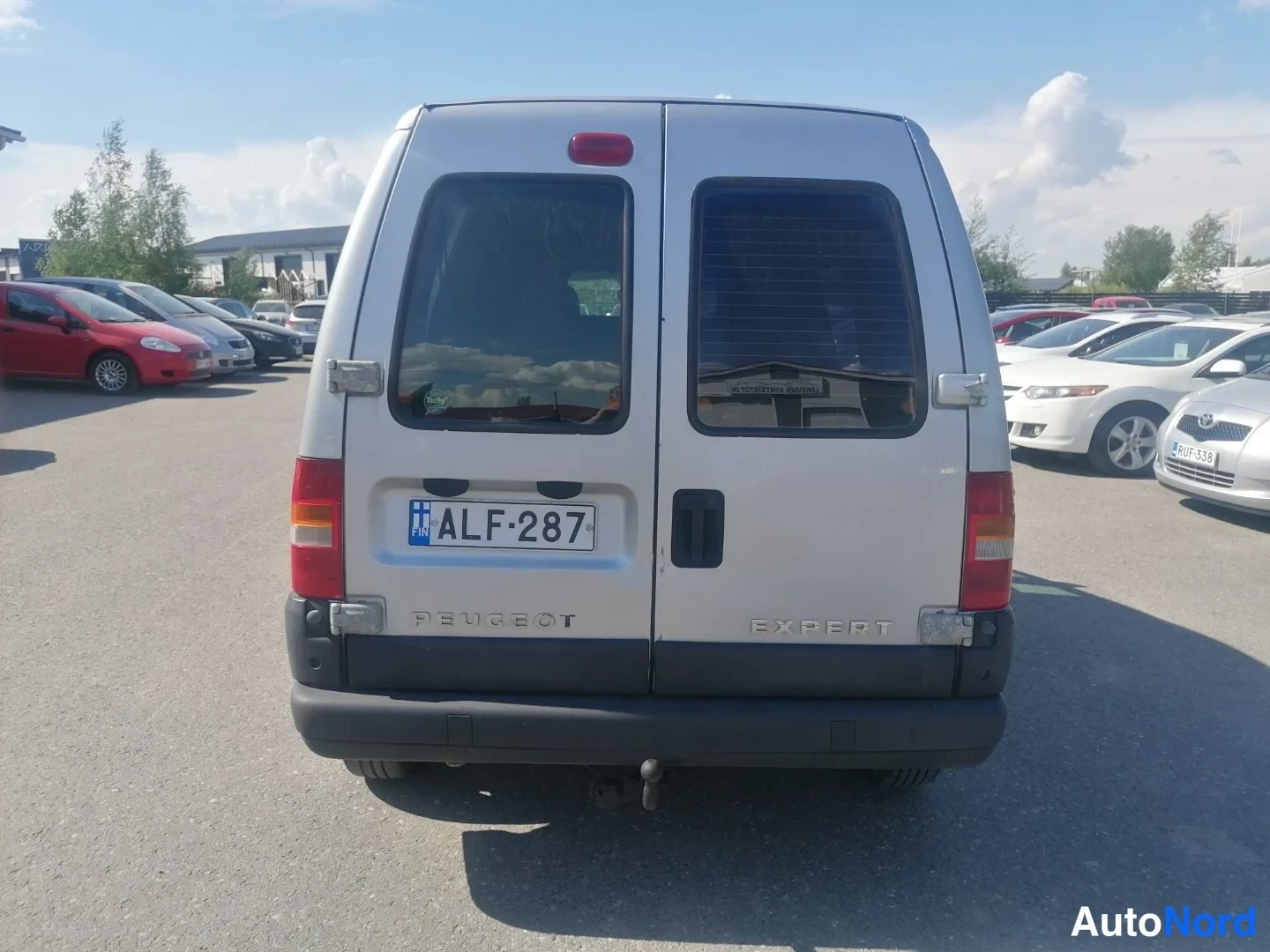 Takaa: Paku eli Peugeot Expert takaa päin kuvattuna, hopeanharmaa kori ja kaksiosaiset takaportaat, rekisterikilpi.