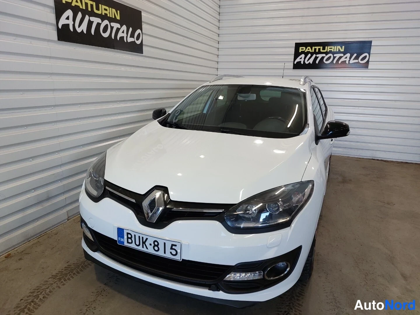Etuviisto, nokka vasemmalle: Renault Megane Sport Tourer -farmari etuvasemmasta kolmannesnäkymästä valkoisena sisätiloissa, rekisterikilpi.