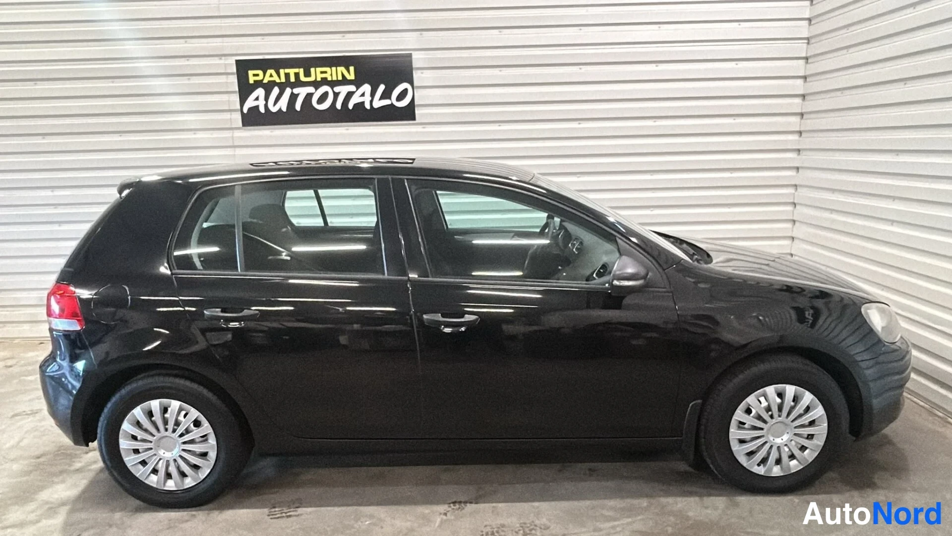 Sivulta: Mustan henkilöauton sivukuva autotallin sisällä.