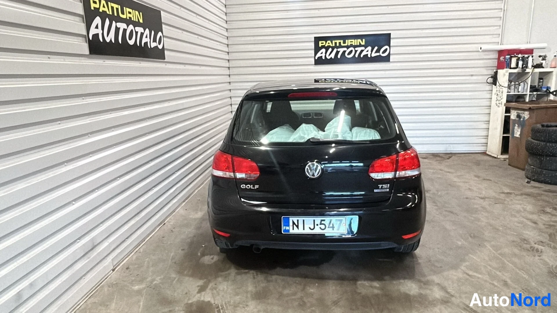 Takaa: Mustan henkilöauton takanäkymä autotallin sisällä.