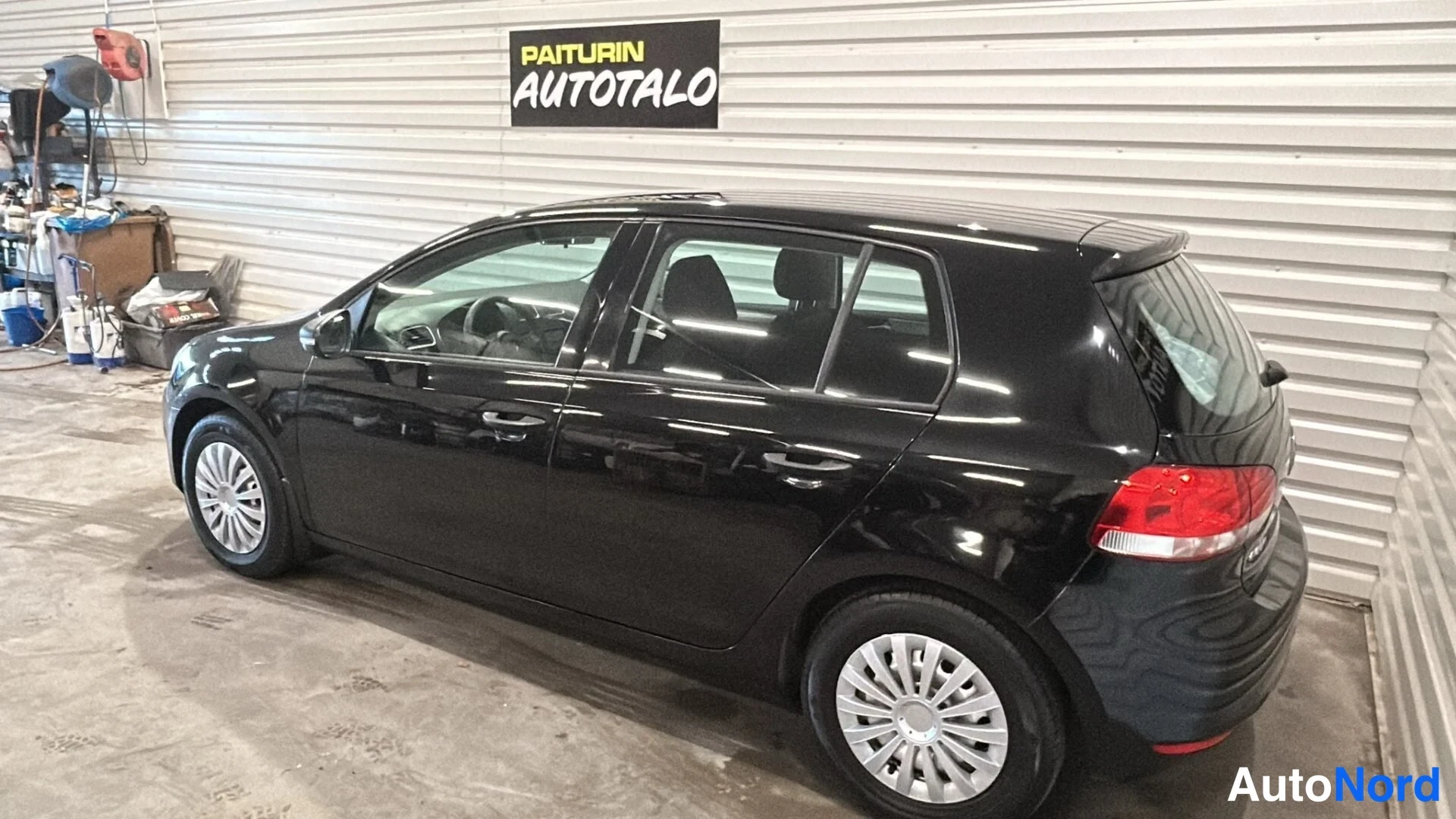 Takaviisto: Mustan Volkswagen Golf -viistoperän takakulma vasemmalta kuvattuna hallissa.