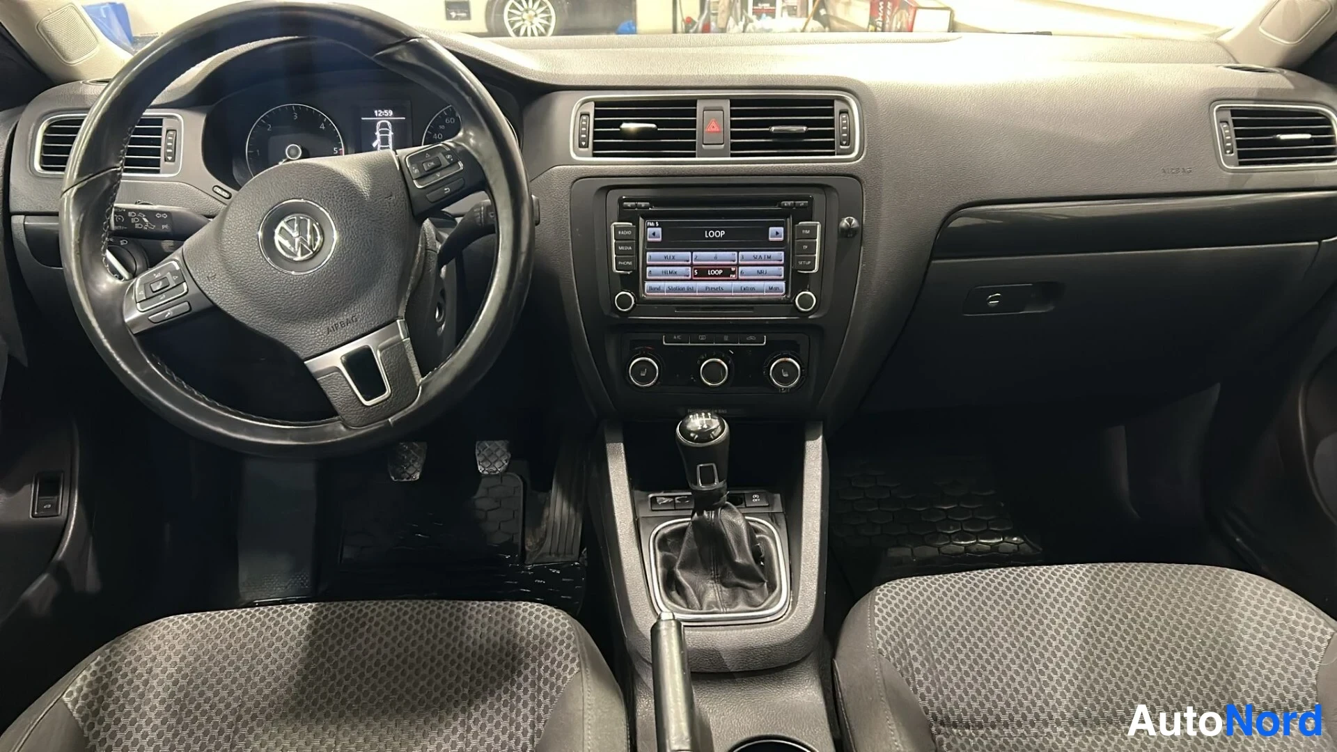 Muu: Volkswagenin ohjaamo: ratissa, keskikonsolissa radio ja manuaalivaihtokeila.