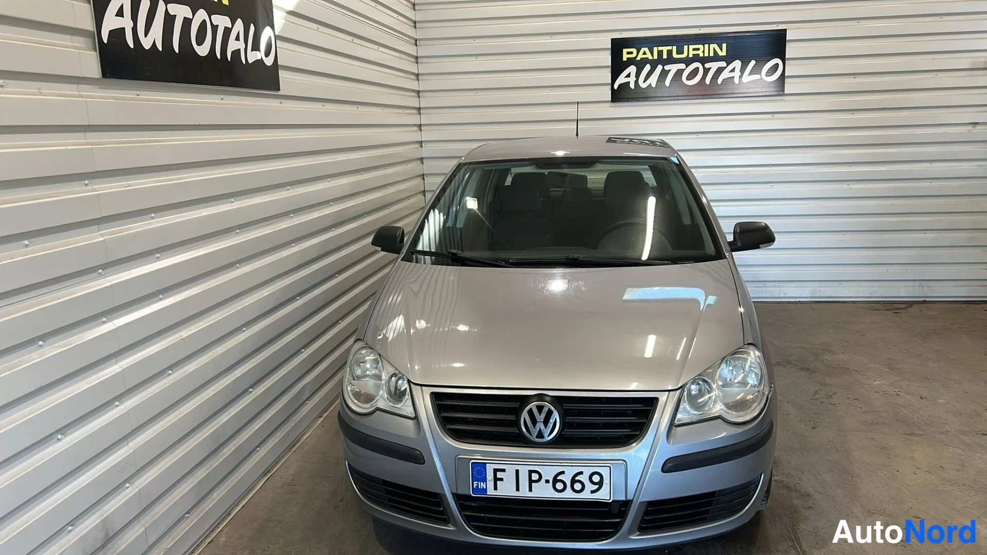 Edestä: Hopeanharmaa Volkswagen Polo suoraan edestä sisätiloissa, rekisterikilpi.