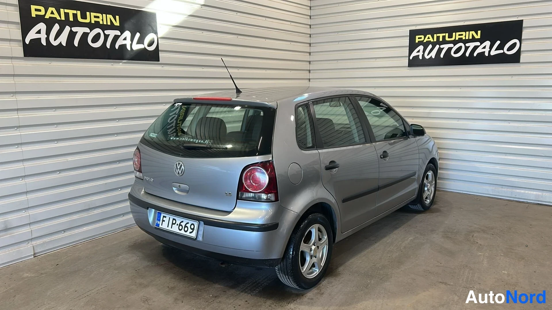 Takaviisto: Harmaa Volkswagen Polo viistoperä takaa sivulta kuvattuna sisätiloissa.