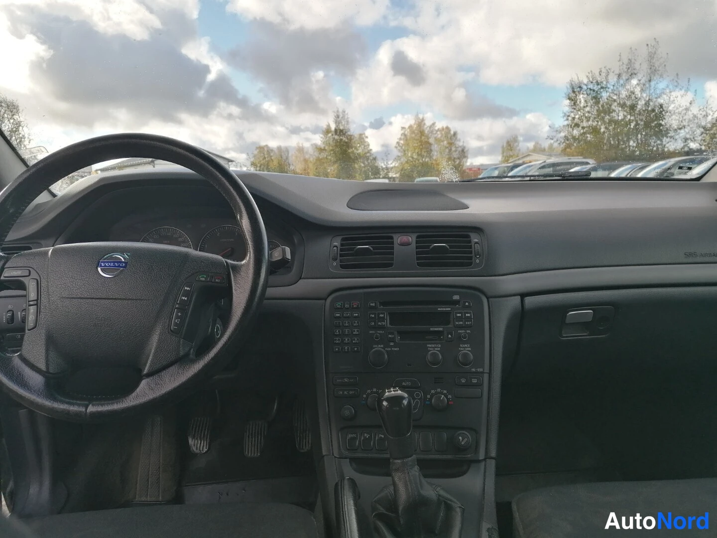 Yksityiskohta: Ohjaamo näkyy etupäästä: musta kuljettajan puolen paneeli, Volvo-ohjauspyörä, manuaalivaihteen keppi ja keskikonsoli radio- ja ilmastointipainikkeineen.