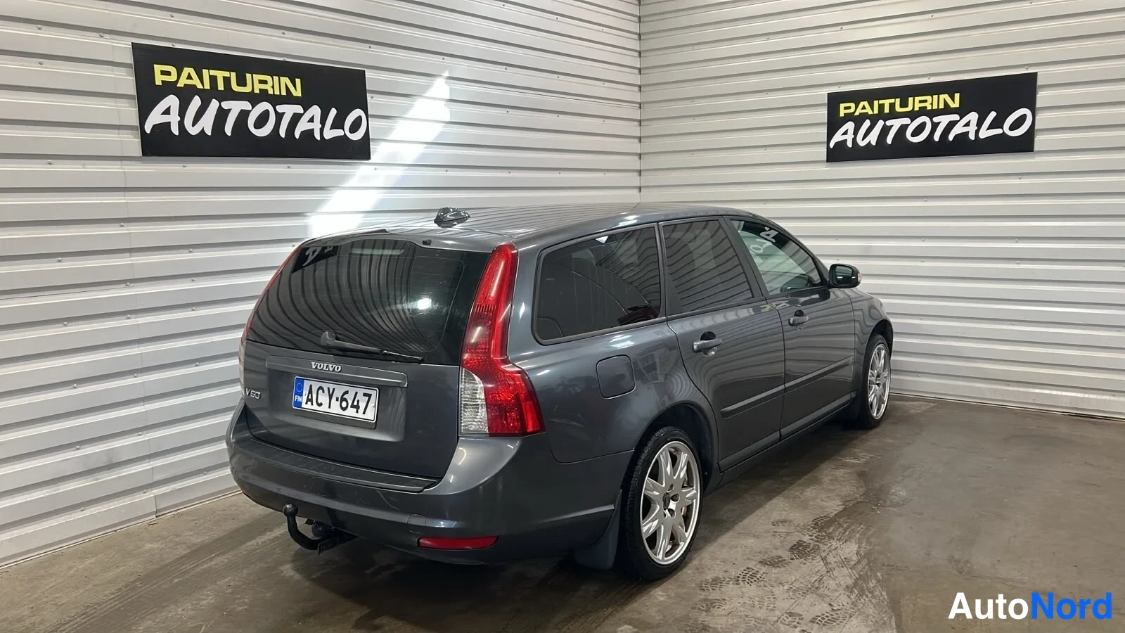 Takaviisto: Tummanharmaa farmariauto takakulmasta, takaosa ja oikea kylki näkyvissä; rekisteritunnus.