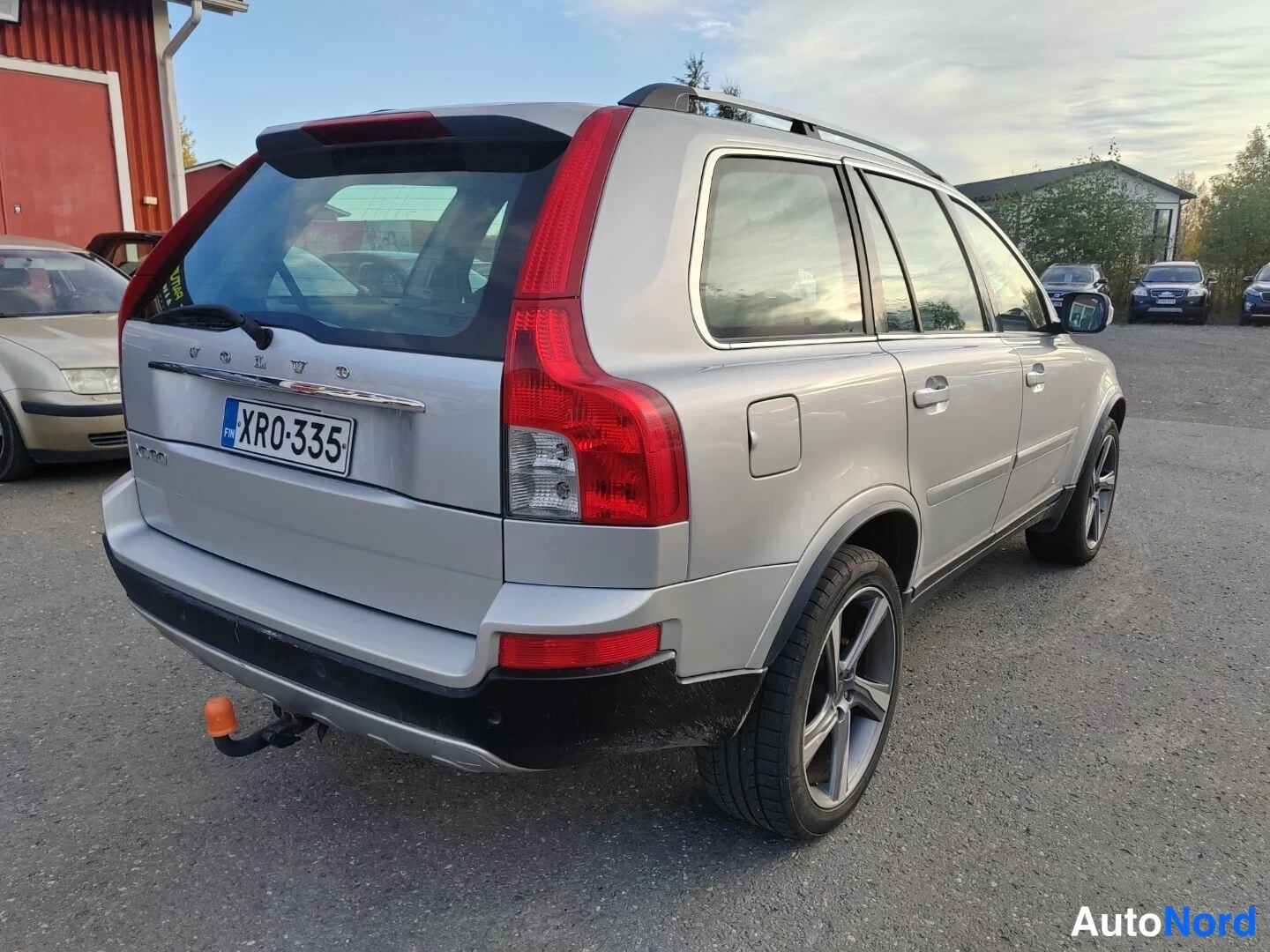 Takaviisto: Hopeanharmaan Volvo XC90:n takaosa ja oikea kylki viistosta, rekisterikilpi XR0-335 ja takavalo näkyvät.