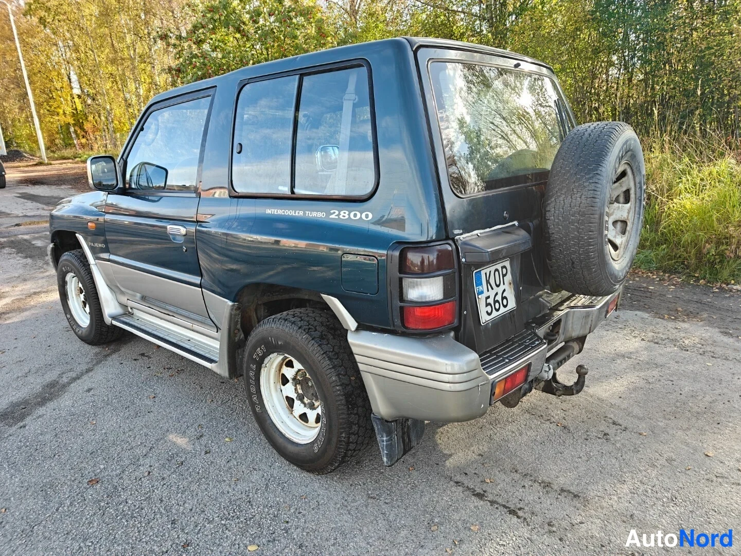 Takaviisto: Mitsubishi Pajero takaa oikealta vasemmalle kuvattuna, varapyörä takaluukulla, rekisteritunnus KOP 566.