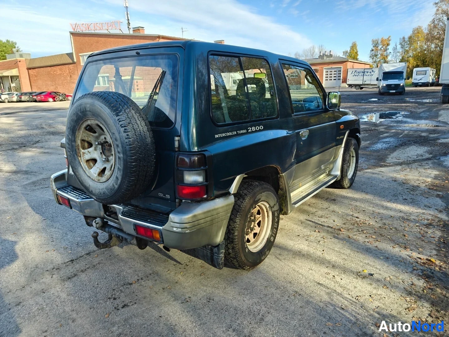 Takaviisto: Taka kolmannesnäkymä tummanvihreästä Mitsubishi Pajarosta; takapuomi, varapyörä takaluukulla ja vasen kylki näkyvät, kyljessä teksti INTERCOOLER TURBO 2800.
