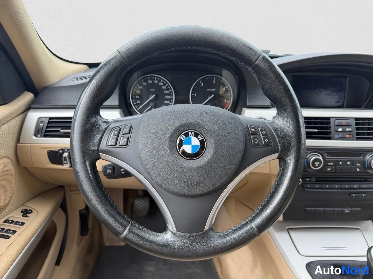 Muu: Ohjaamossa BMW-merkkinen ohjauspyörä, kojelautamittarit ja beigea sisustusta näkyvät keskikonsolin molemmin puolin.