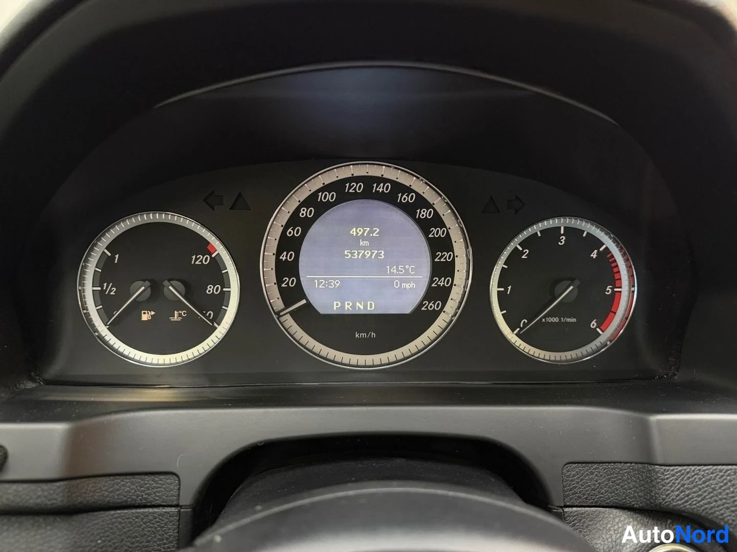 Edestä: Mittaristojen lähikuva: nopeusmittari asteikolla 0–260 km/h, matkamittari 537973 km, bensiinimittari puolessa välissä ja lämpötila 14,5 °C, vaihde P.