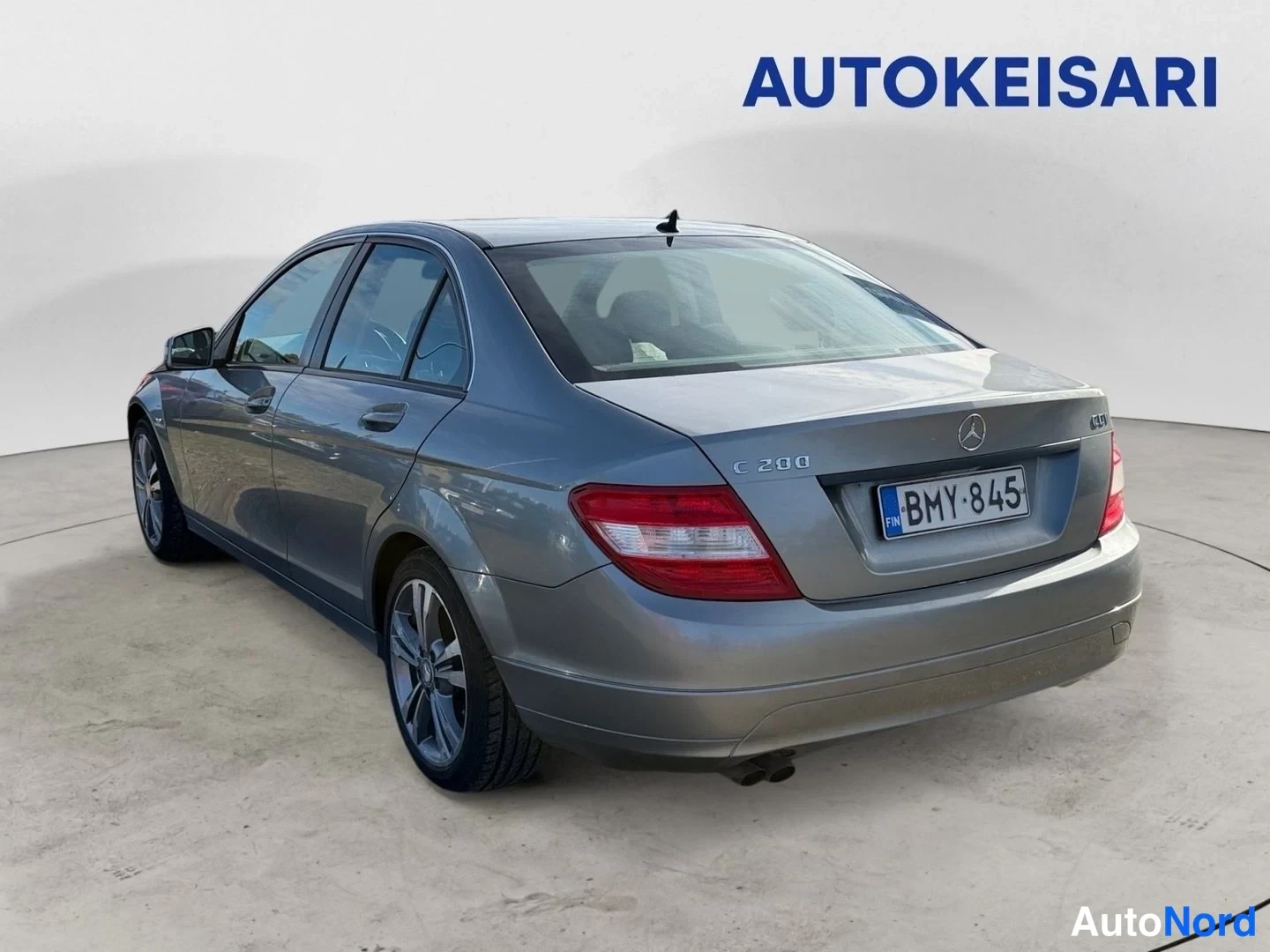 Takaviisto: Mercedes-Benz C-sarjan sedan takaokoliskuva vasemmalta, hopeanharmaa kori, rekisterikilpi, tavaratilan kannessa merkintä C 200.