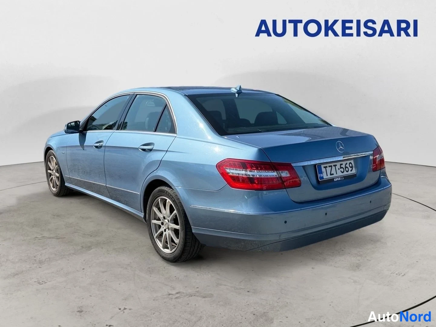 Takaviisto: Sininen Mercedes-Benz E-sarjan sedan kuvattu takaa kolmanneltasektoralta, perävalot ja takapuoli näkyvissä studiossa.