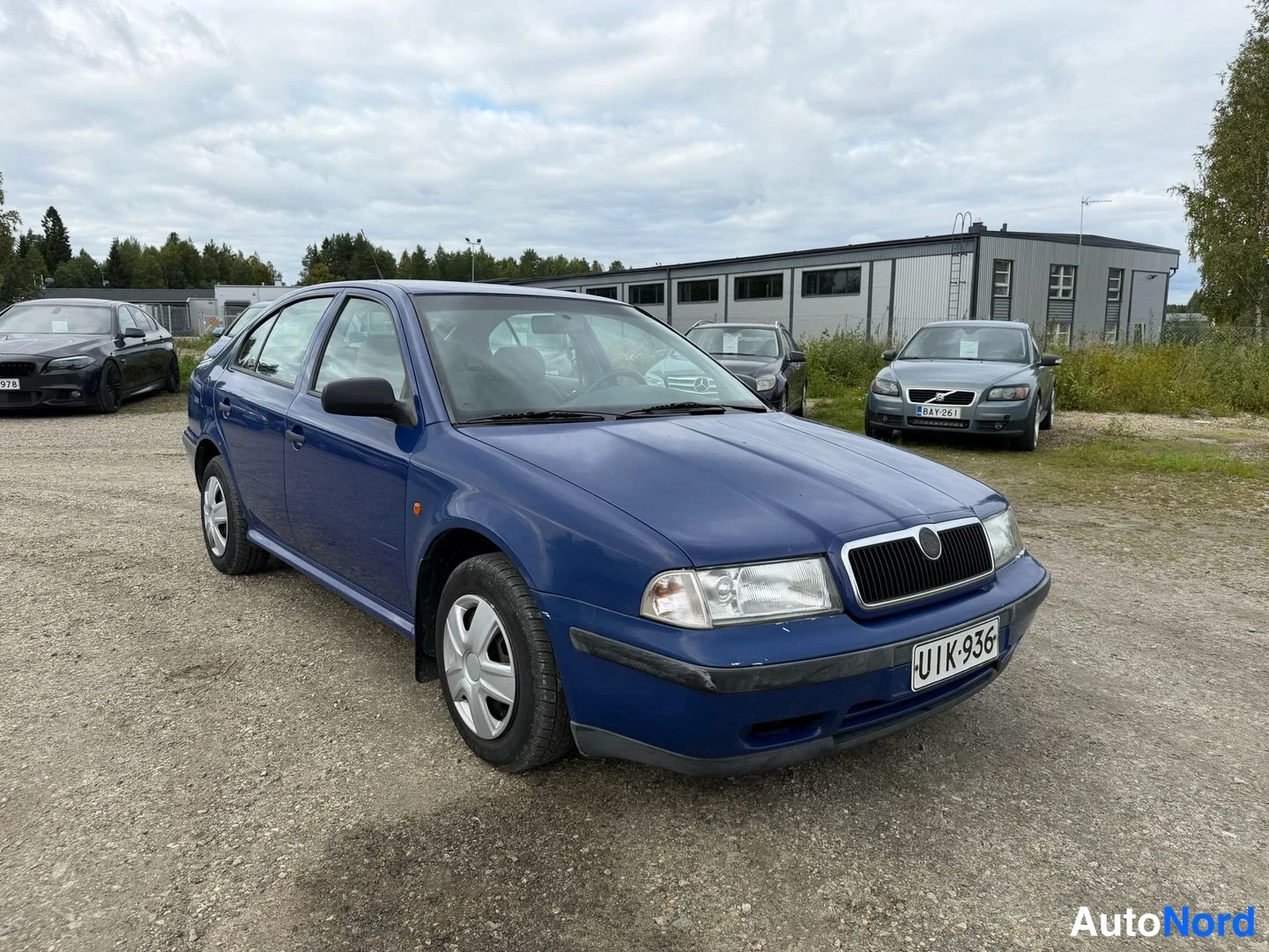 Etuviisto, nokka oikealle: Sininen Skoda Octavia -henkilöauto etuosa kolmesta neljäsosasta oikealta kuvattuna soraparkkipaikalla.