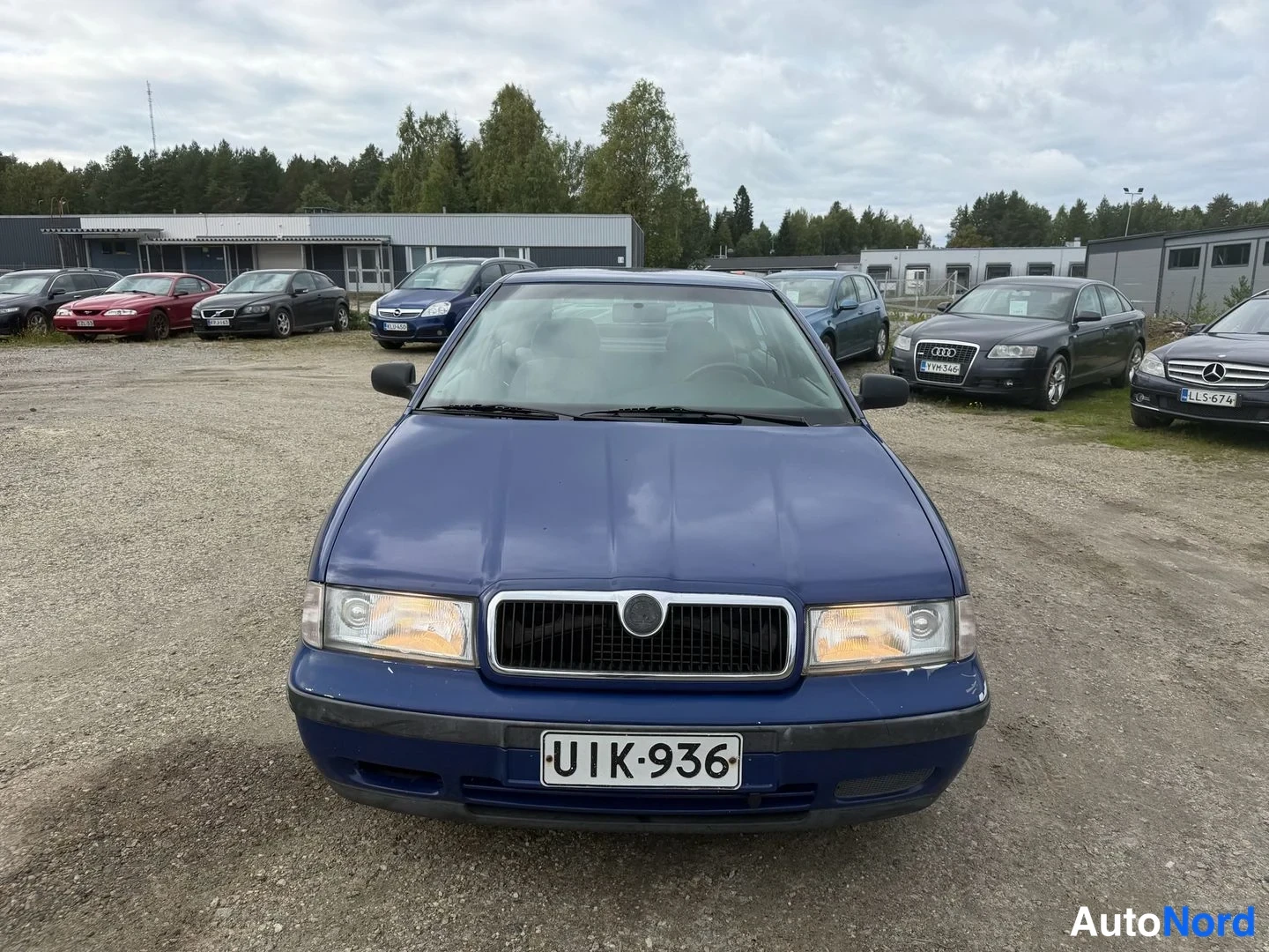 Edestä: Sininen Skoda Octavia -henkilöauto suoraan edestä kuvattuna soraparkkipaikalla, rekisteritunnus.