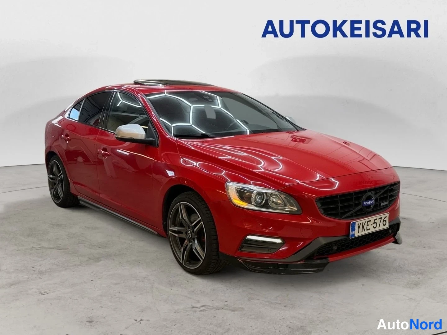 Etuviisto, nokka oikealle: Punaisen Volvo S60 -sedanin etukoivakulman kuva; maski, sumavalot, hopeapeilit ja tummat kevytmetallivanteet näkyvissä, rekisteritunnus.