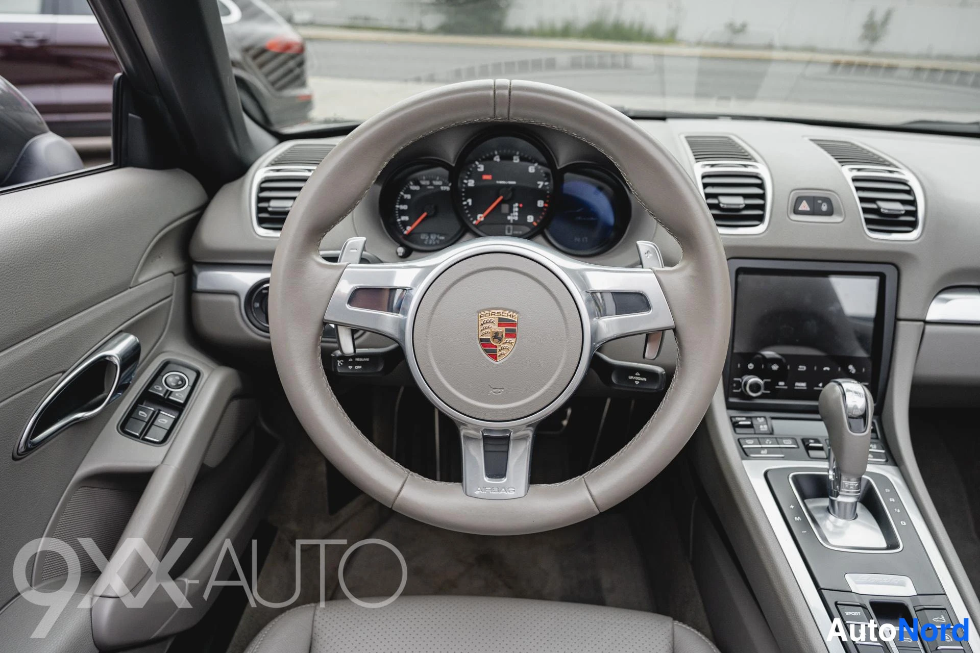 Takaviisto: Porsche-ohjauspyörä ja mittaristo lähikuvassa, beigea nahkaa ja hopealustoja.