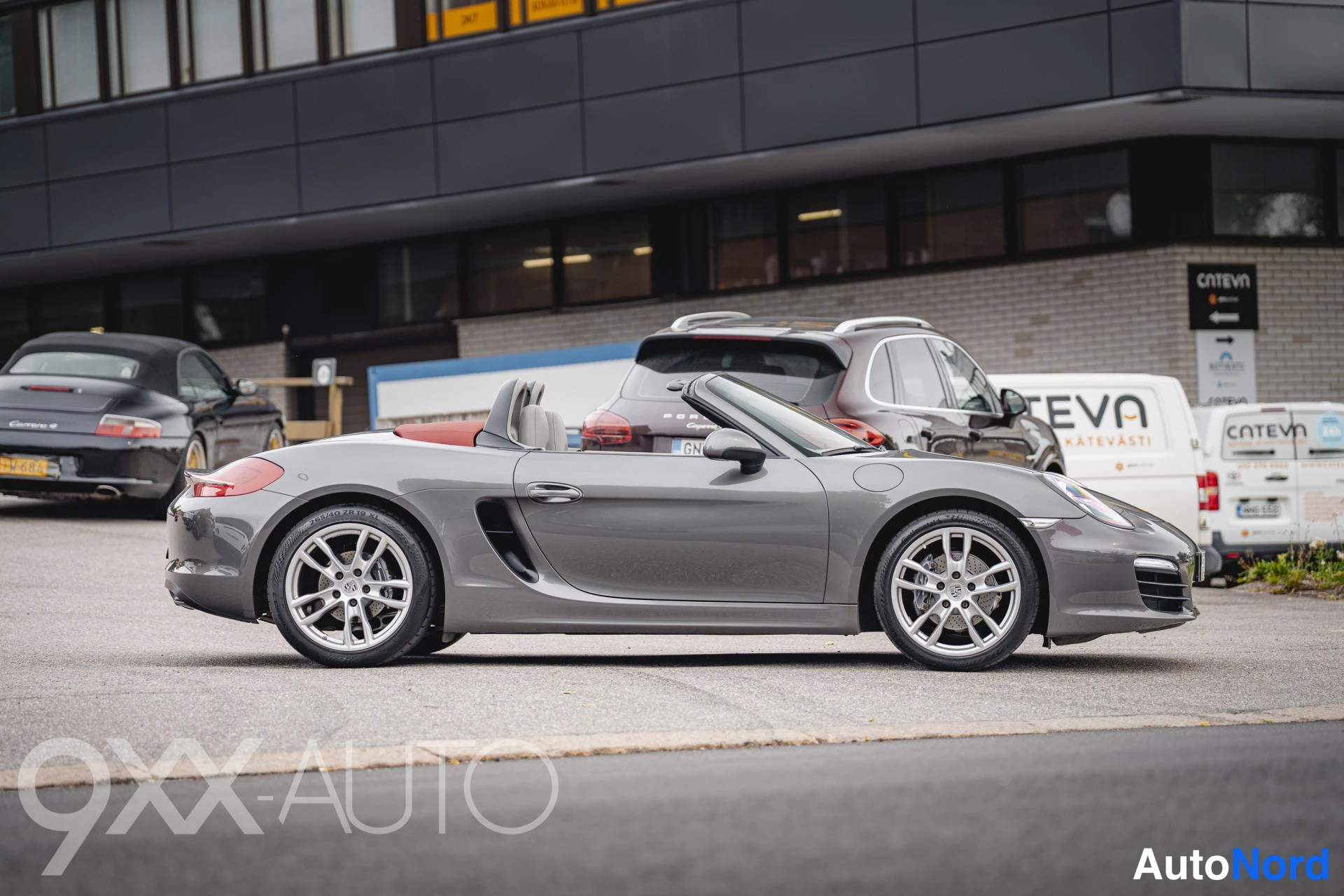 Etuviisto, nokka oikealle: Porsche Boxster-avoneva front three-quarter -kuva oikeasta etukulmasta, katto auki, kori harmaa.