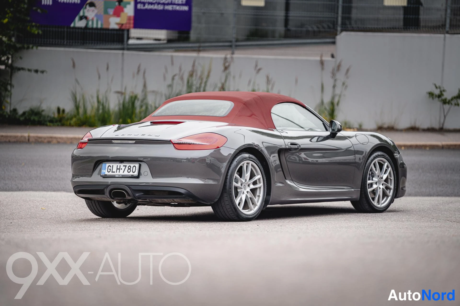 Takaviisto: Porsche Boxster takaa viistosti: harmaa koripelti, punainen kangaskatto ja -rekisterikilpi.
