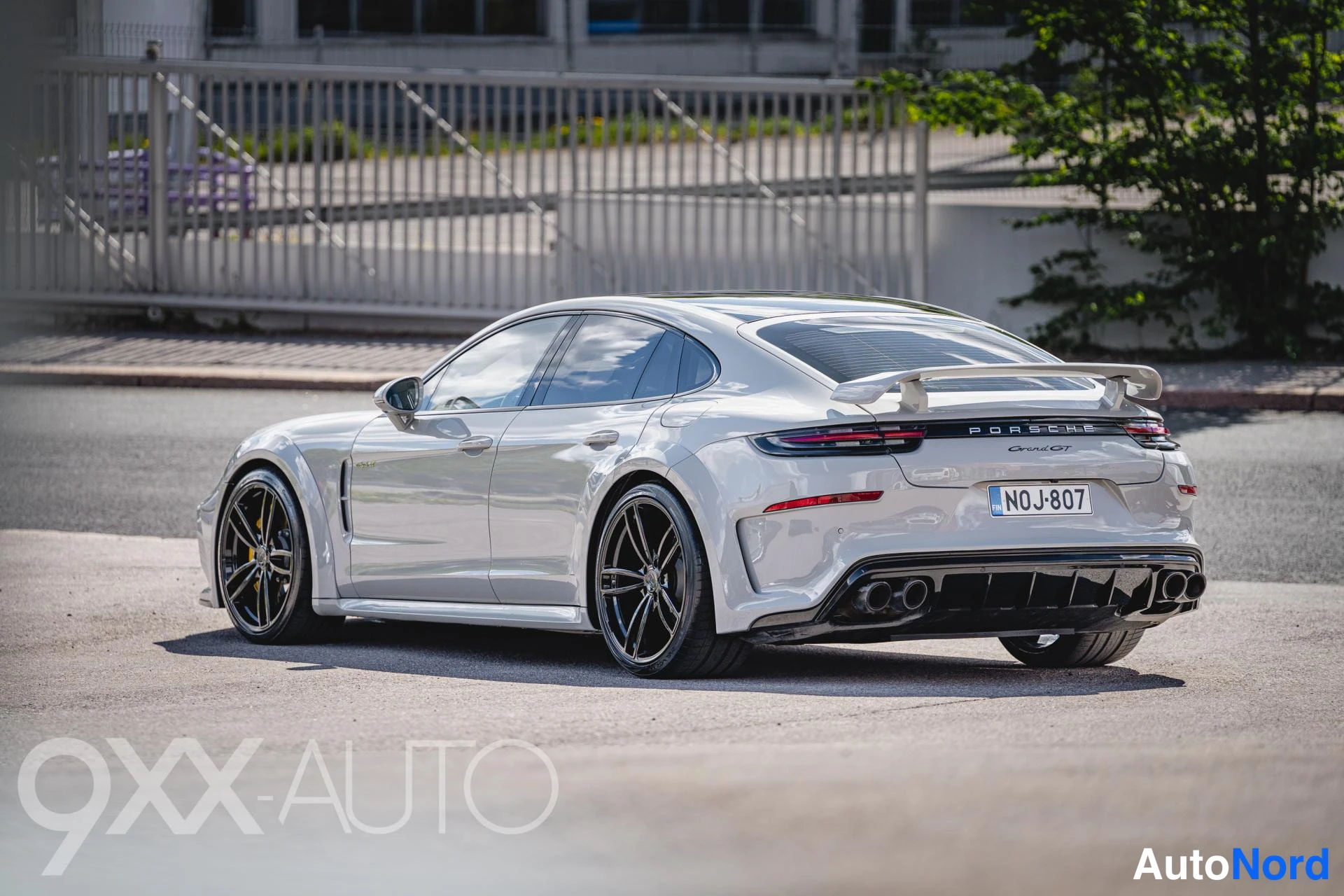 Takaviisto: Hopeanharmaa Porsche Panamera takaviistosta toiselta puolelta, suuri takasiipi, mustat neljä pakoputkea ja tummat vanteet, rekisteritunnus.