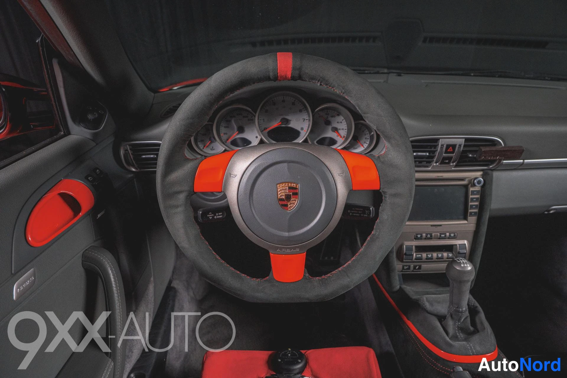 Muu: Porsche-merkki rattiin, sekäkankaalla/nahkalla päällystetty ohjauspyörä punaisin korianneeri- ja ompele-yksityiskohdoin, mittarit ja manuaalivaihtokytkin näkyvi