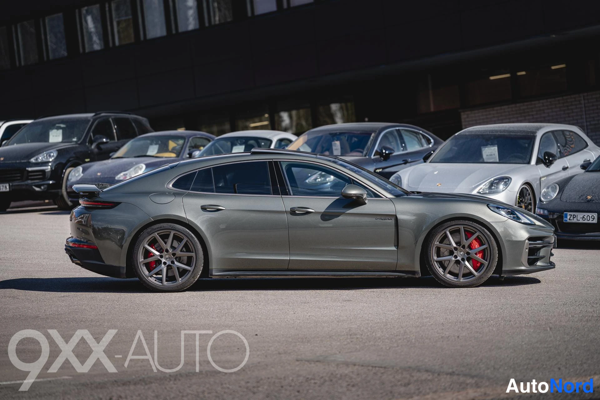 Sivulta: Tummanharmaa Porsche Panamera kylkikuvassa vasemmalta, päättyvä takavalo ja punaiset jarrusatulat näkyvissä.