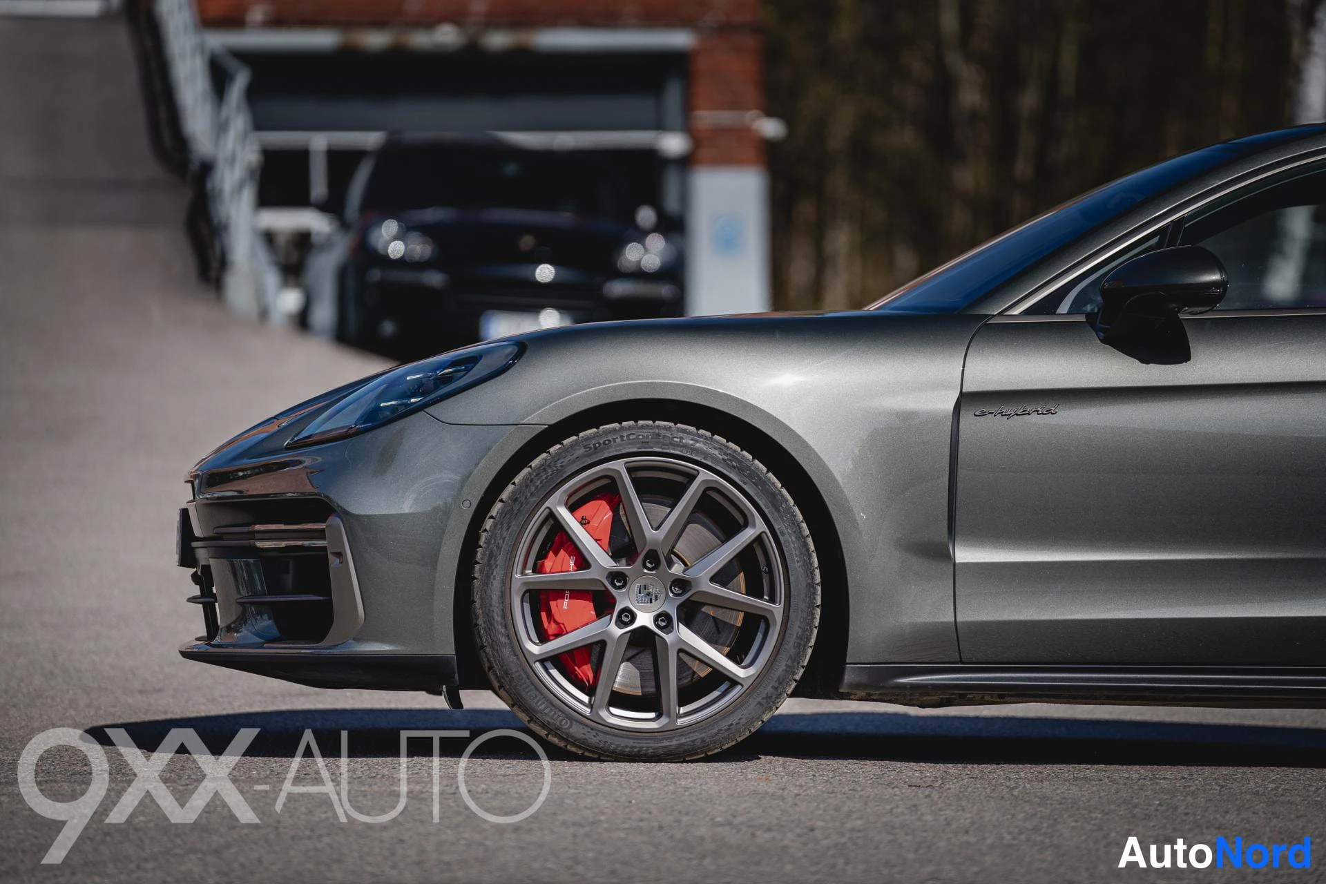 Etuviisto, nokka vasemmalle: Porsche Panamera -mallin keula vasemmalta kuvattuna, edessä harmaat kevytmetallivanteet ja punaiset jarrusatulat.