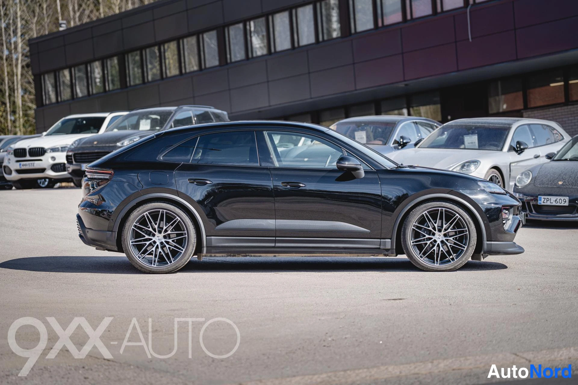 Takaviisto: Mustan coupé-SUV:n sivuprofiili vasemmalta puolelta, takavalot ja etupuskuri näkyvissä, harmaat monipuoliset kevytmetallivanteet.