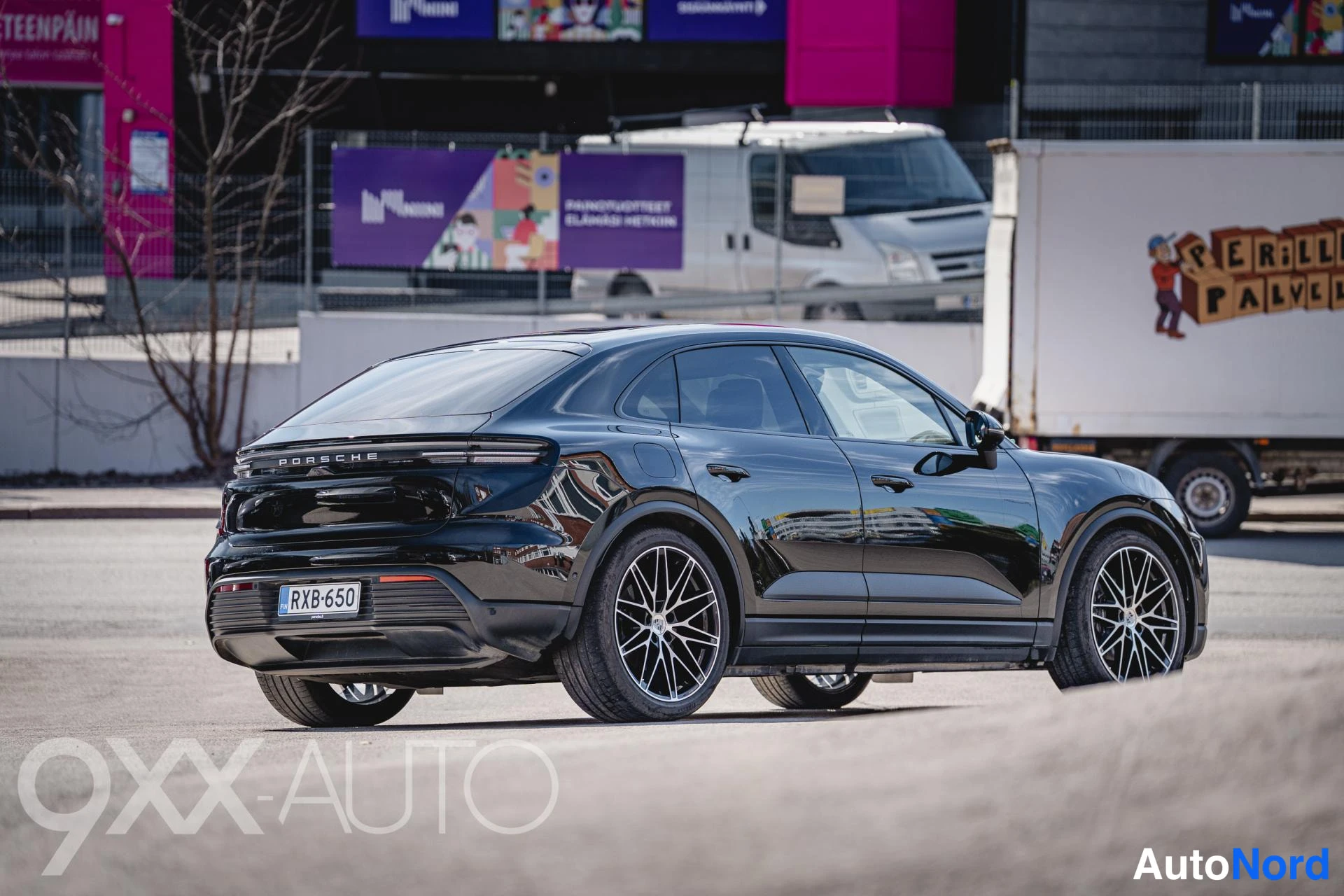 Takaviisto: Mustan SUV:n takaviisto vasemmasta kulmasta, PORSCHE-teksti takana, rekisterikilpi.