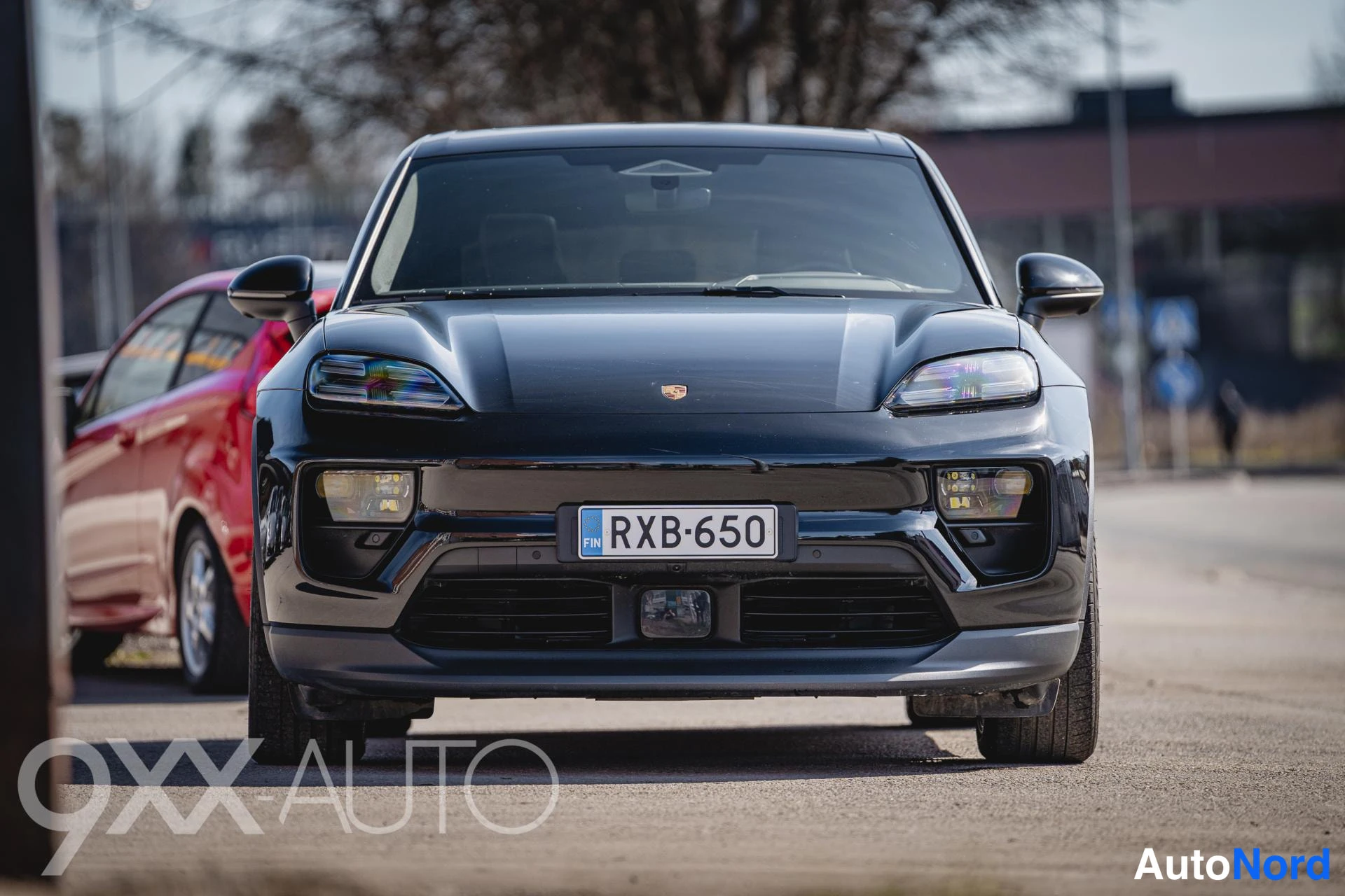 Edestä: Mustan SUV:n etunäkymä, valot ja etupuskuri näkyvissä, rekisterikilpi.