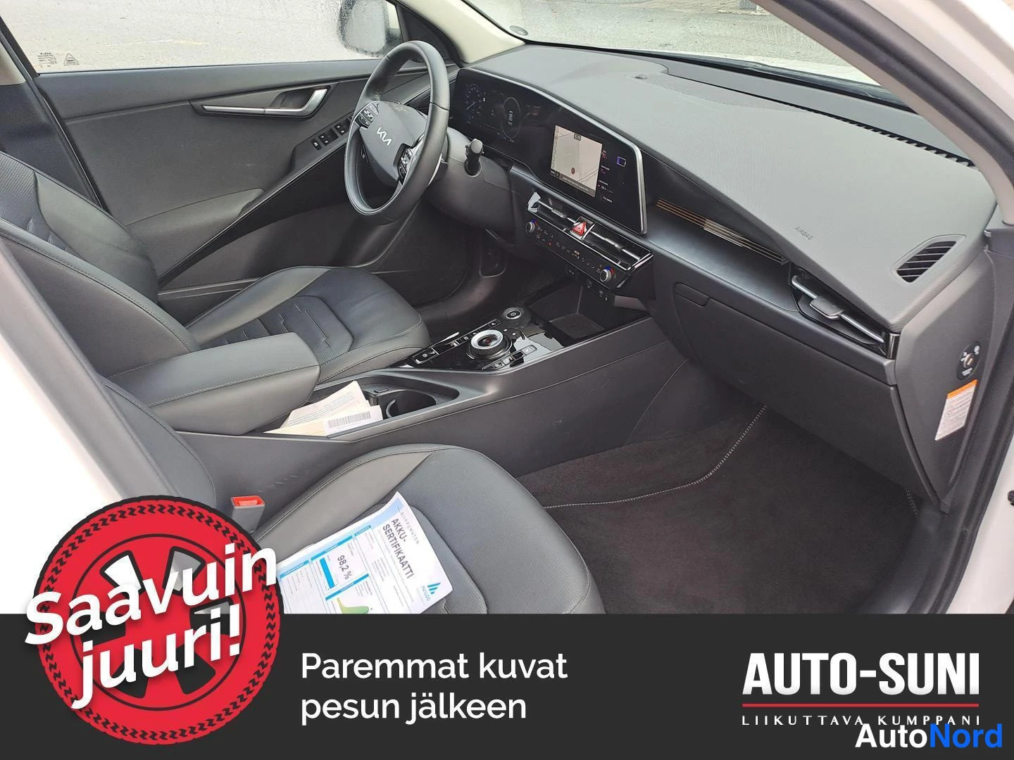 Muu: Auton etuistuintilat ja kojelauta kuvattuna matkustajan puolelta; näkyy keskinäyttö, vaihdevalitsin ja etumatkat istuimet.