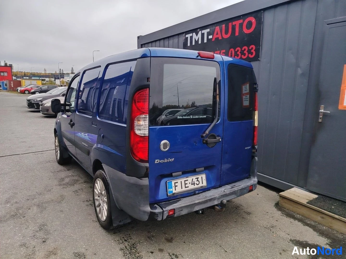 Takaviisto: Sininen Fiat Doblo takaosa takakulmasta, takaluukussa Doblo-teksti ja -kilpi, kytkinupti takapuskurissa.