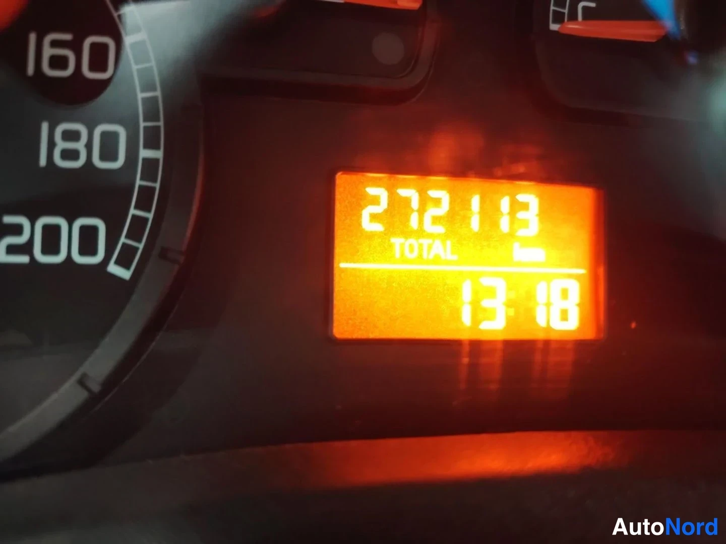 Yksityiskohta: Kojetaulun digitaalinäytön lähikuva: kokonaisajolukema 272 113 km (TOTAL) ja kello 13.18; vasemmalla osa nopeusmittarin asteikosta (160–200).