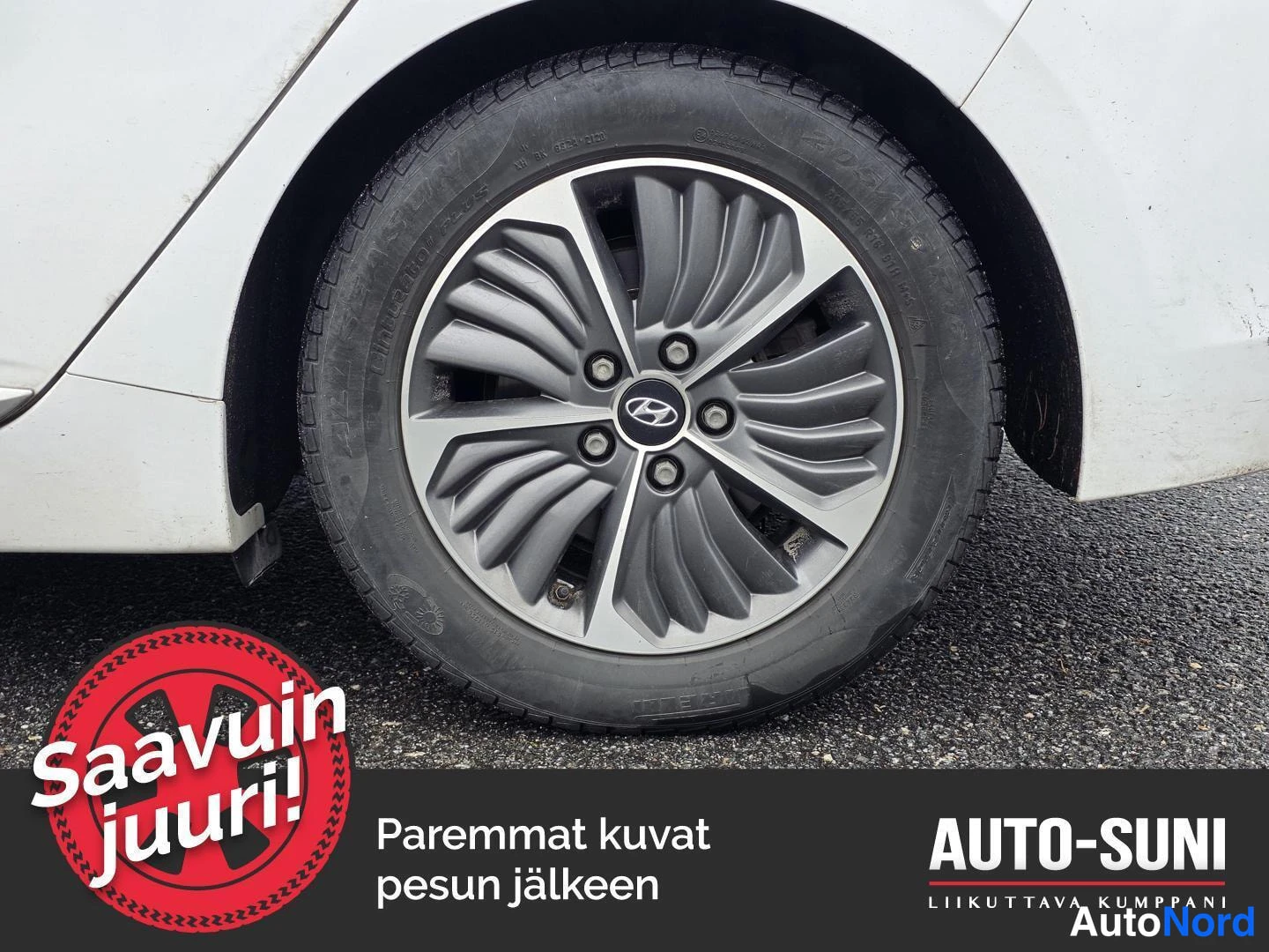 Yksityiskohta: Lähikuva auton valkoisen rungon vasemmasta edespyörästä ja renkaasta. Pyörän keskiössä on Hyundai-logo.