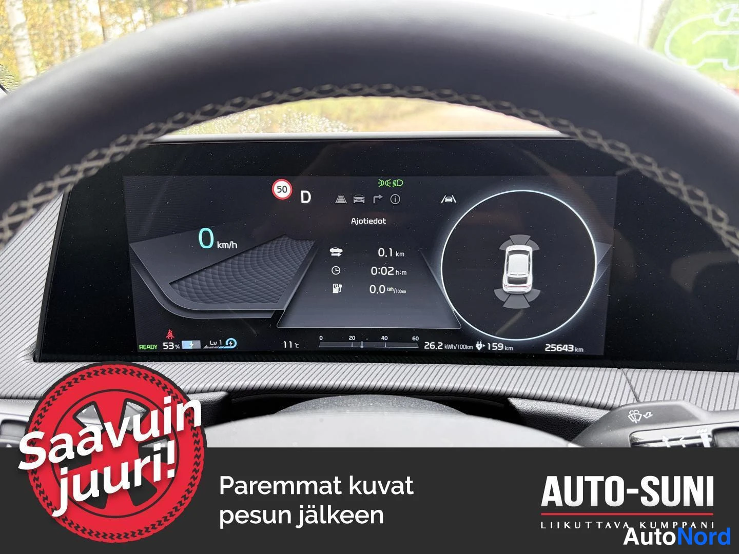 Muu: Close-up of a digital instrument cluster behind a black multi-function steering wheel with visible paddle shifters. The dashboard screen shows the car at 25643