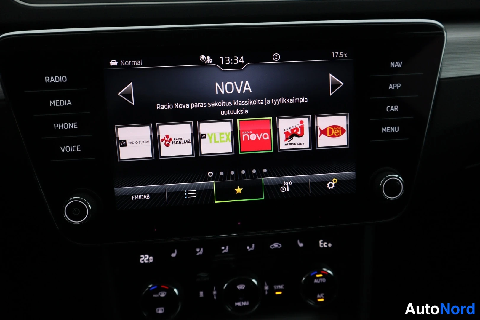 Ohjaamo: Suuri kosketusnäyttöruutu, jossa on radiosto nimestä NOVA. Näytössä on painikkeet RADIO, MEDIA, PHONE, VOICE vasemmalla ja NAV, APP, CAR, MENU oikealla. Ilmasto