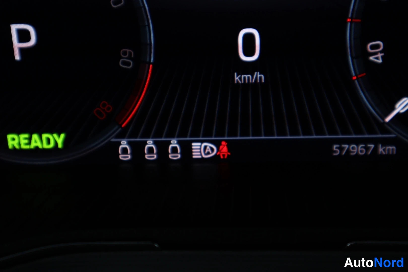 Yksityiskohta: Kokonainen mittariston kuvaus. Mittari näyttää nopeuden 0 km/h, valikoiden P-asennon ja READY-ilmanmerkin. Oikealla kulmajuoksutustunnus 57967 km. Kolme eteenpä