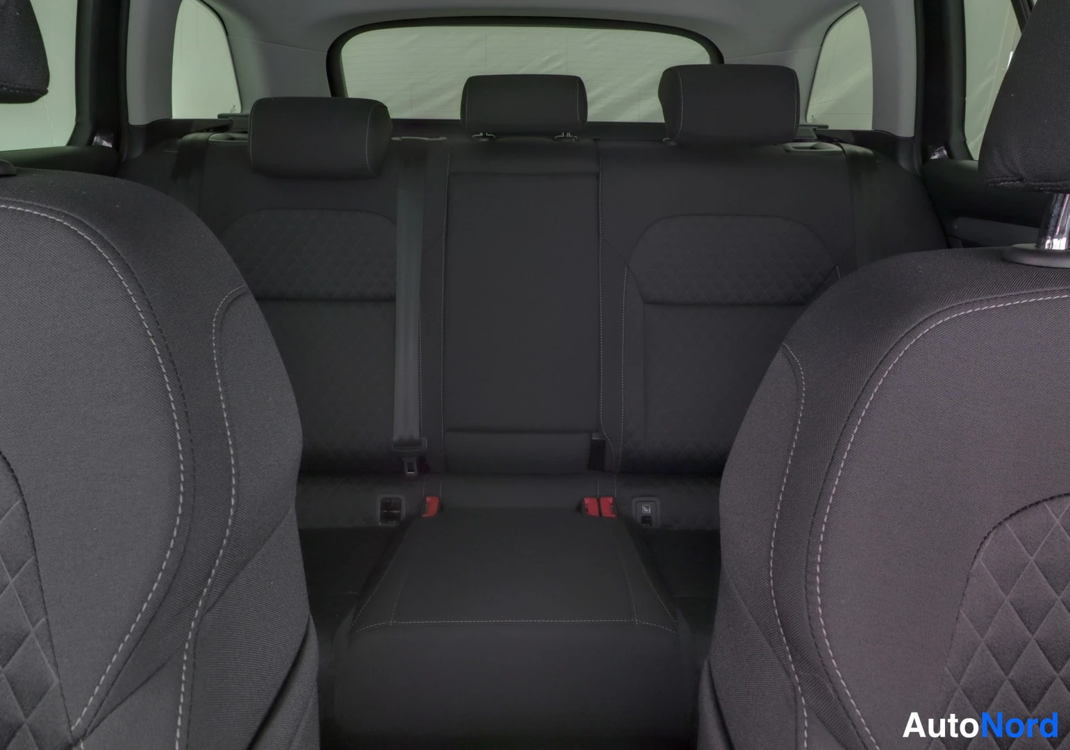 Takaistuimet: Rear seat interior shot from behind the front seats looking towards the back. Three rear headrests are visible across the back bench. Diamond stitching pattern