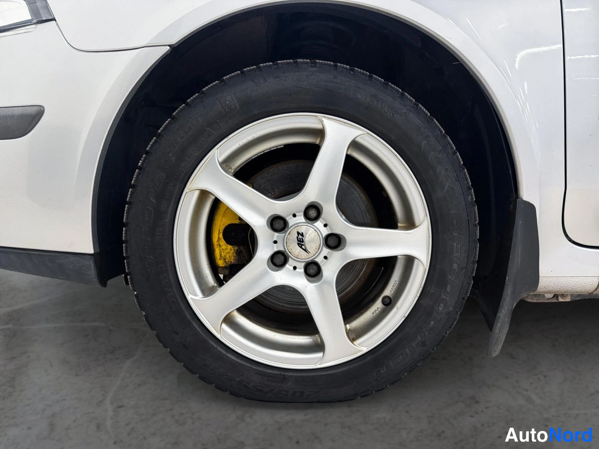 Yksityiskohta: Auton pyörän lähikuva: viisikanta­metalliharja AEZ-vanteella ja BFGoodrich-renkaalla, jarrusatula keltainen.