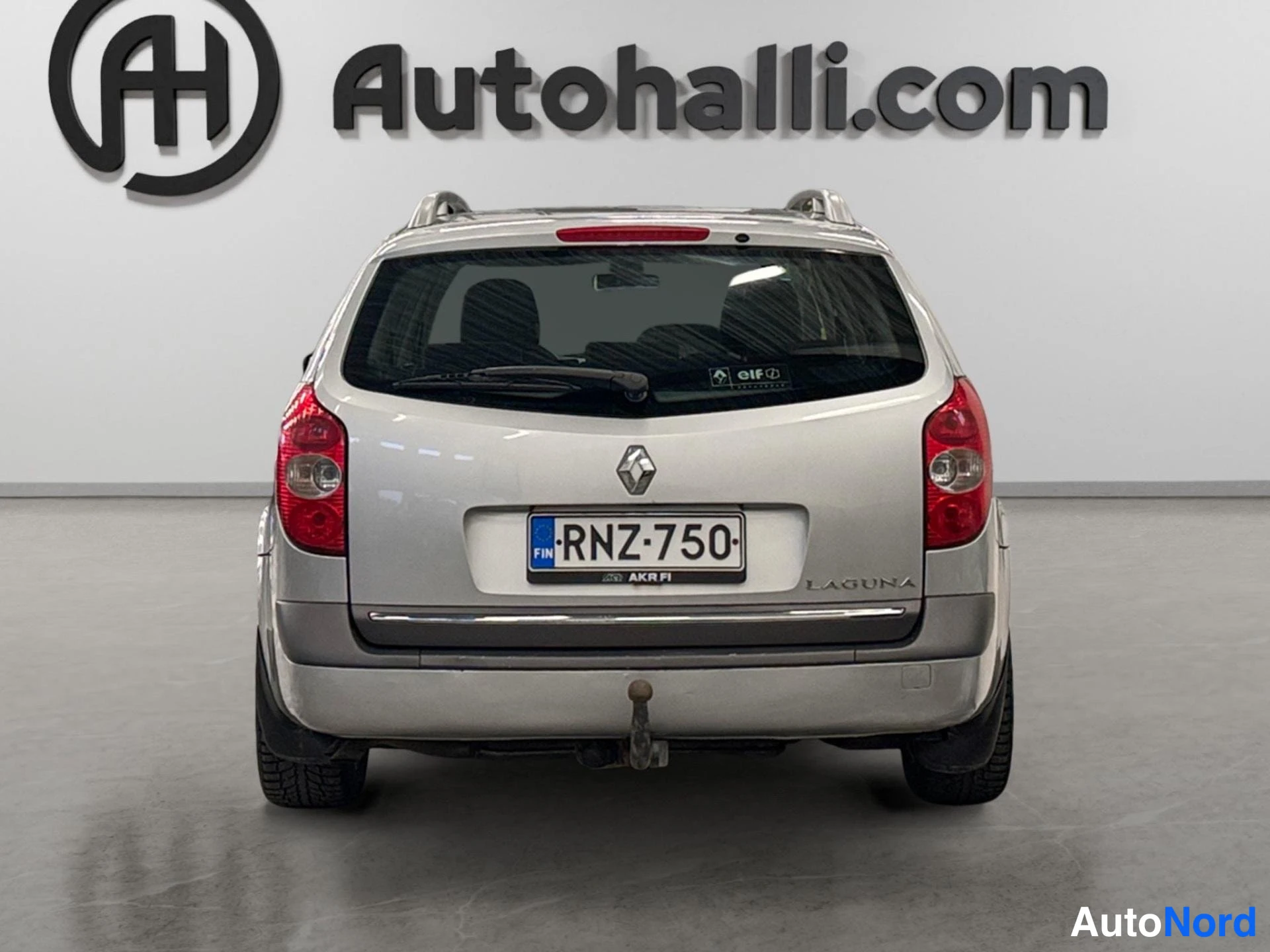 Takaa: Hopeanharmaan Renault Laguna -farmarin takaosa suoraan takaa; rekisterikilpi, tavaratilan kannessa LAGUNA-teksti ja takapuskurissa vetokoukku.